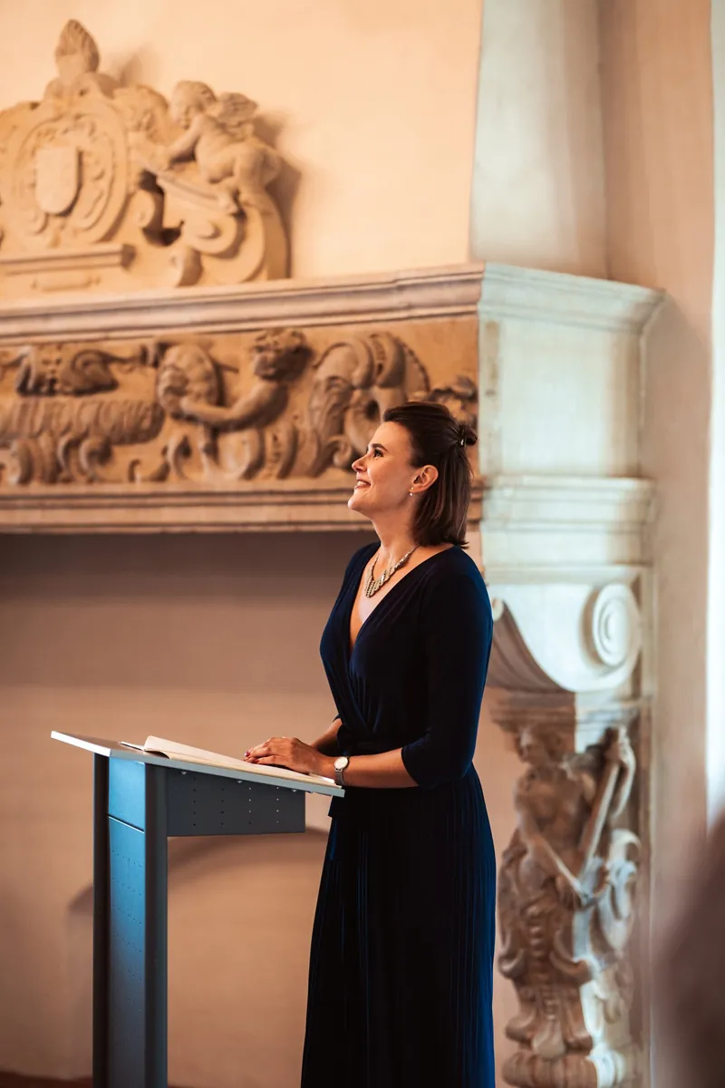 Julia Holla als Traurednerin am Rednerpult vor einem historischen Kamin
